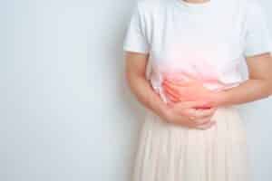 A cropped shot of a woman holding her abdomen, experiencing pain that could be managed with a hysterectomy